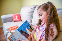Girl reading book from the CuriousCaptain box. Through learning & adventure, StoryCaptain empowers parents to raise little explorers.