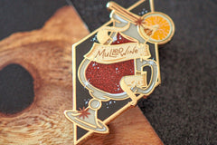 Gold plated, hard enamel pin depicting Mulled wine in a translucent enamel bottle. Printed details and scroll, plus an orange slice.
