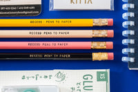 Close-up picture of notebook, pencils, stickers, pen, eraser, and business card. These items are an example of what may be included.