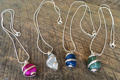 Wrapped Stone semi precious stones on a silver chain. Showing a pink, a clear, a dark blue, and a teal. 