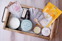 An array of self-care items specifically curated for hand pampering. The set includes a pair of plush spa gloves and a pourable candle
