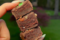Close-up image of hand holding three boozy brownie bites - Guinness, Irish Cream and Bourdon Brownie Bites.