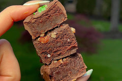 Close-up image of hand holding three boozy brownie bites - Guinness, Irish Cream and Bourdon Brownie Bites.