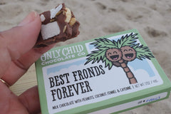 Small box of Only Child's milky smooth coconut chocolate bar at the beach. It's nutty, crunchy and spicy.