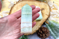 A photo of a pistachio calcite obelisk offered by Soul Gifts Crystals as an example of a crystal of the month.
