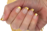 A hand showcasing Gold Tips Nail Wraps on all fingers with a golden-colored paint on a white wall as the backdrop.