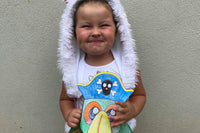 A child wearing a fluffy hat smiles while holding a colorful pirate parrot craft from the Little Dreamers Club monthly subscription box