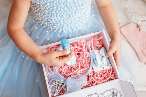 A pink Petite Princess Box featuring a tiara, hair accessories, and decorative ribbons, ideal for kids' accessories box