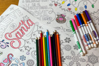 Coloring pages laying on the table along with markers and coloring pencils. Reindeer and Santa are the theme.