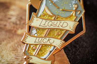 Gold plated, hard enamel pin depicting liquid luck in a translucent enamel bottle. Printed details and scroll, the potion is gold glitters.