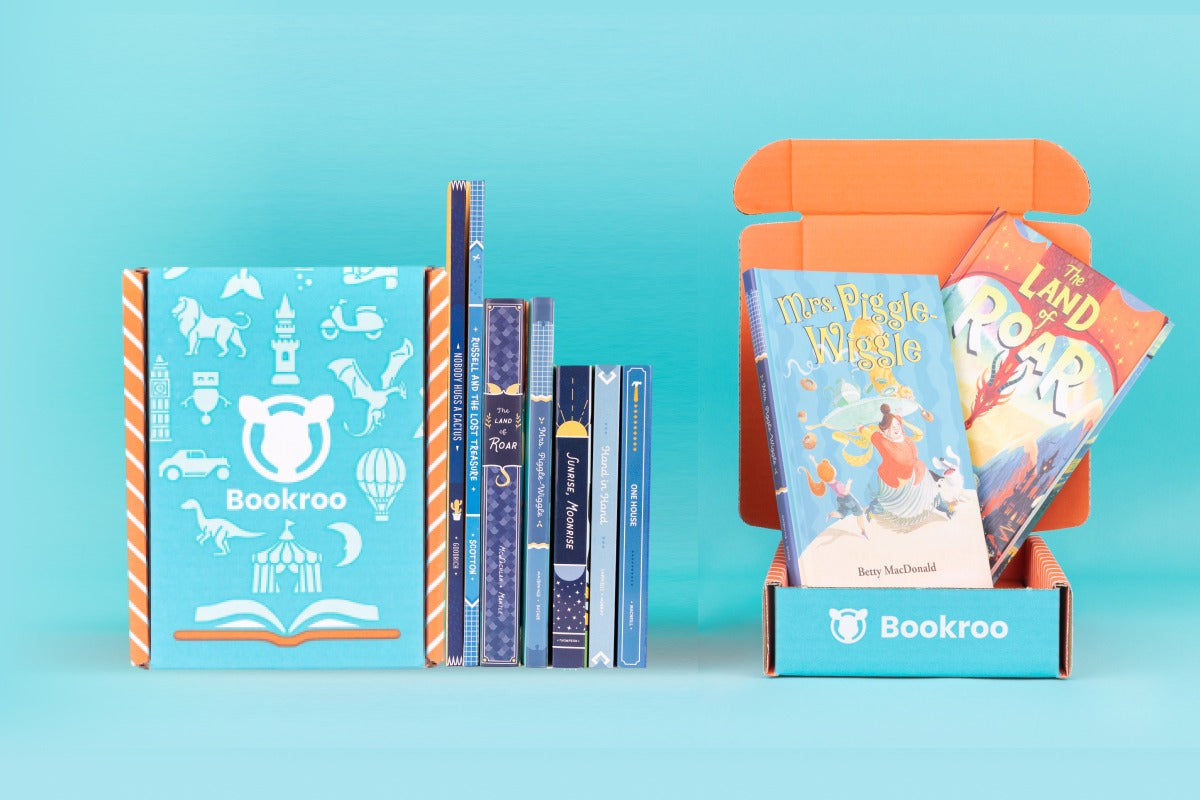 Two children reading books from Bookroo's Tween Book Club subscription on a colorful rug with additional books nearby
