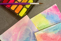 Completed Activity Trunk art activity: Water color painted hearts on stationery cards alongside water color pallet and brush