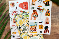 A selection of summer themed stickers including BBQ, lemonade and women, shown on a wooden desk with fronds overlapping.  