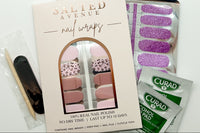 Set of Nail Wraps in packaging and another set outside of packaging, 2 alcohol prep pads, a mini nail file and a cuticle tool.