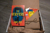 Book titled the Verifiers by Jane Pek resting in box next to book wrapped in brown paper and twine stuffed with items