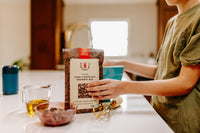 In the  Purposed Box HOME Edition by Monet Carpenter, there is a throw blanket, brownies, prayer book, plastic free hair ties, and guide.
