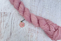 A mini Skein of Hand Dyed Merino Sock Weight Yarn and a coordinating stitch marker. Suitable for knitting and crocheting 