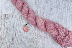 A mini Skein of Hand Dyed Merino Sock Weight Yarn and a coordinating stitch marker. Suitable for knitting and crocheting 