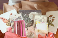 Subscription box including prints, a journal, notepad, pens, and stickers