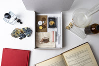 An open Matter subscription box showcasing an ammonite fossil and various science artifacts for the curious mind