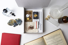 An open box displaying a selection of items that have been featured in past Matter boxes, featuring an ammonite fossil
