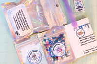 Blue Christmas slime kit contents in a flat lay, glitter, jello, instructions, glue and activator. Blue and purple colors
