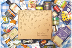 A Culinarie LUXE box surrounded by cooking ingredients. The box is decorated with illustrations of ingredients and cooking utensils.