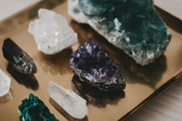 brown platform with different crystals on it. there are 8 crystals showing two white two green and two purple