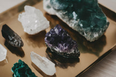 brown platform with different crystals on it. there are 8 crystals showing two white two green and two purple