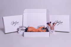 Glam Luxe Subscription Box: Including rosegold diamond brush set, heart shaped bling earrings, and a peach long sleeve dress.