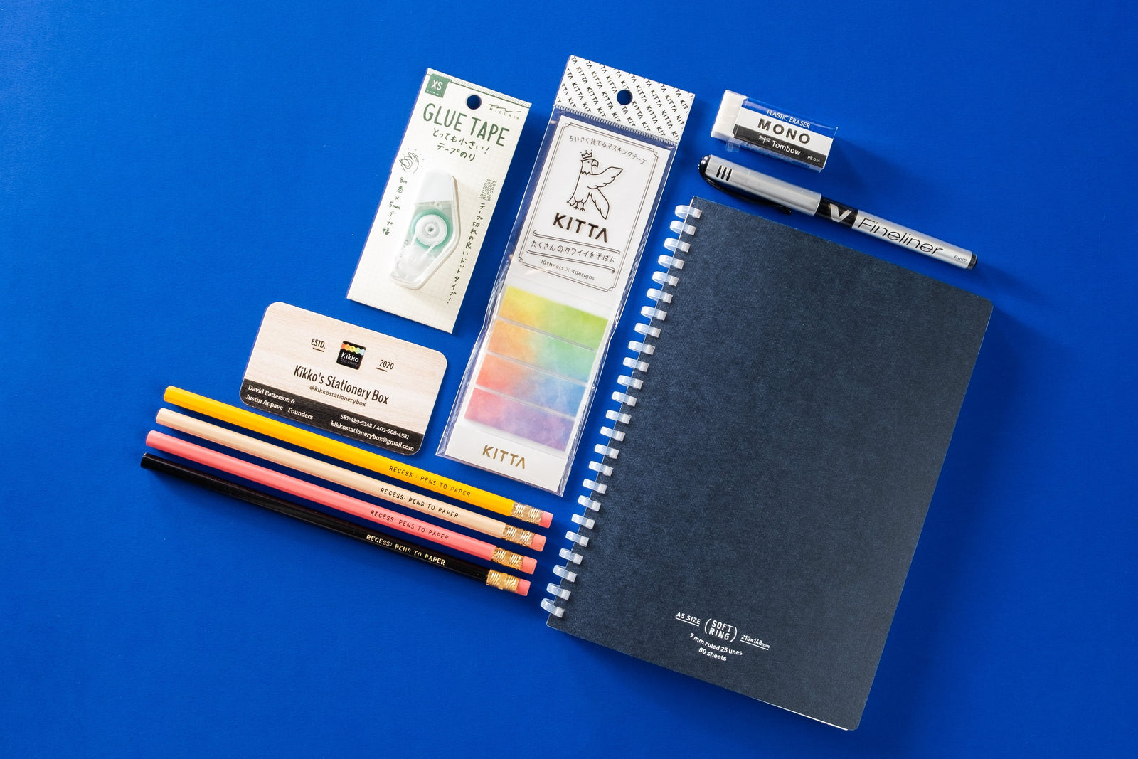 Close-up picture of notebook, pencils, stickers, pen, eraser, and business card. These items are an example of what may be included.