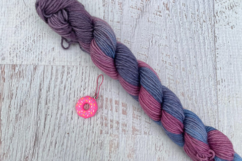 A mini Skein of Hand Dyed Merino Sock Weight Yarn and a coordinating stitch marker. Suitable for knitting and crocheting 