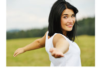 a female with black hair and green eyes is smiling and has arms spread open in a T-position. She seems happy.