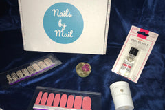 A Nail Obsession subscription box that says nails by mail and various nail stickers and top coat for nails.