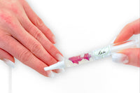 Woman's hands with natural french nails applying the Rose Botanical Nail Pen to her cuticle and nail beds.