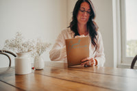 young adult female opening her greeting card subscription mailer - a Kraft flat mailer with greeting cards and envelopes inside