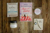 A red mug filled with three packets of Moonstruck milk chocolate, featured in the Peace & Pages monthly subscription box
