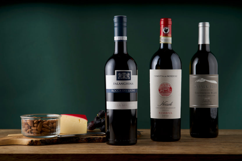 3 bottles of wine next to a board with almonds, cheese and grapes, from a The Standard - Wine Club subscription box.