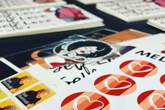 Side angle view of stacks of cards being sorted with envelope seals, stamps and a bonus pack of stickers.