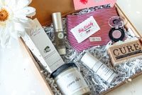 An open Canadian Beauty subscription box filled with skin care items, makeup, a candle and zipper pouch.