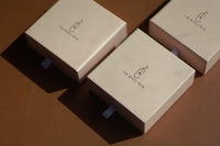 Three small thejewelpick gift boxes sitting on a brown surface.