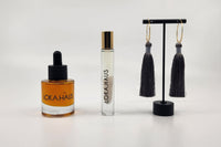 LOKA.HAUS beauty: 'Duality Oil' in amber, center 'Intensity Parfum Roller', & luxe tassel earrings on right. Elegance in a subscription box.